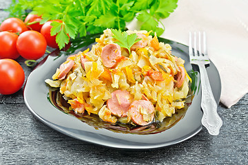 Image showing Cabbage stew with sausages in black plate on wooden board