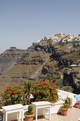 Image showing tables with flowers and view of town on the caldera volcanic cli