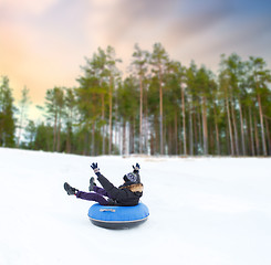 Image showing happy young man sliding down hill on snow tube