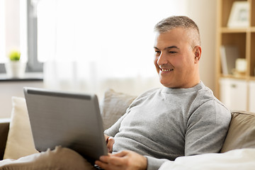 Image showing man with laptop computer sitting on sofa at home