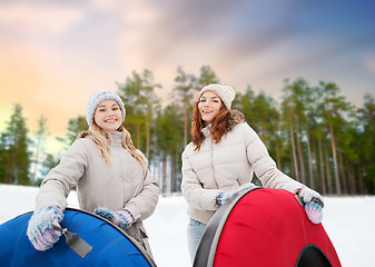 Image showing happy teenage girls with snow tubes in winter