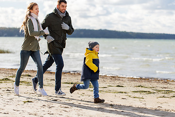 Image showing happy family running along autumn beach