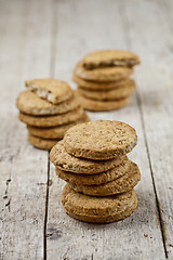 Image showing Three stacks of fresh baked oat cookies on rustic wooden table.