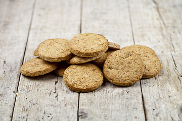Image showing Fresh baked oat cookies heap on rustic wooden table.