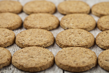 Image showing Fresh baked oat cookies closeup on rustic wooden table.