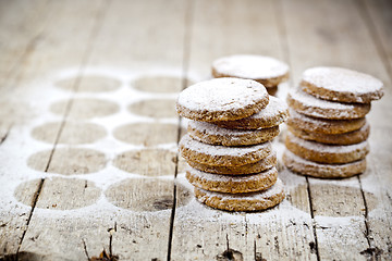 Image showing Fresh oat cookies stacks with sugar powder on rustic wooden tabl