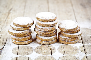 Image showing Fresh oat cookies stacks with sugar powder on rustic wooden tabl