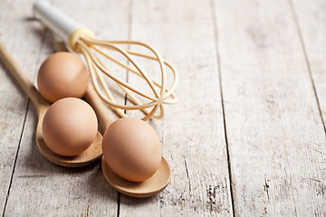 Image showing Chicken eggs and kitchen utensil on rustic wooden table backgrou