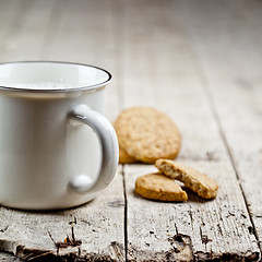 Image showing Cup of fresh milk and some homemade baked oat cookies on rustic 