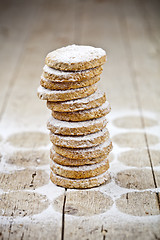 Image showing Fresh oat cookies stack with sugar powder closeup on rustic wood