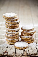 Image showing Fresh oat cookies stacks with sugar powder closeup on rustic woo