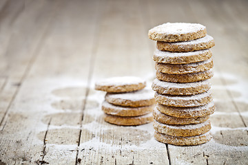 Image showing Fresh oat cookies stack with sugar powder closeup on rustic wood