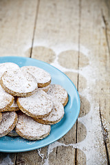 Image showing Fresh baked oat cookies with sugar powderon blue ceramic plate o