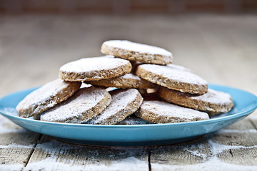 Image showing Fresh baked oat cookies with sugar powderon blue ceramic plate o