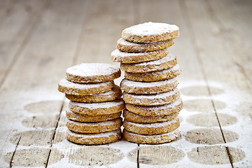 Image showing Fresh oat cookies stacks with sugar powder closeup on rustic woo