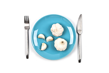 Image showing Organic garlic on blue plate, fork and knife on white background