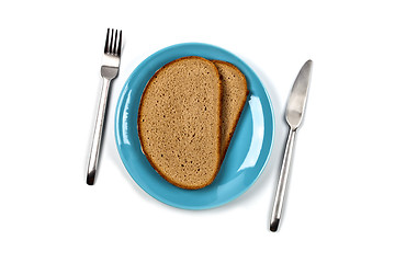 Image showing Fresh baked bread slices on blue plate, fork and knife on white 