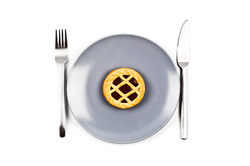 Image showing Chocolate tart on grey ceramic plate, fork and knife on white ba