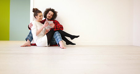 Image showing Young Couple using digital tablet on the floor