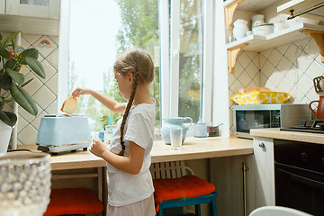 Image showing Beautiful girl in her kitchen in the morning preparing breakfast