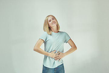 Image showing The happy freckled woman standing and smiling against gray background.