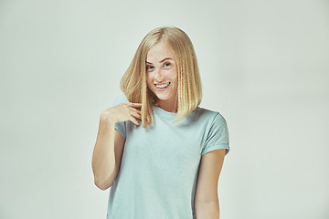 Image showing The happy freckled woman standing and smiling against gray background.