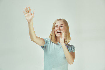 Image showing The happy freckled woman standing and smiling against gray background.