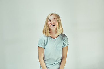 Image showing The happy freckled woman standing and smiling against gray background.