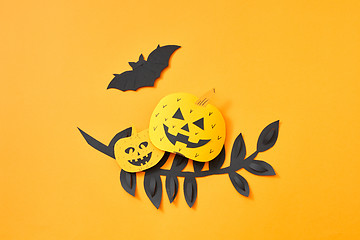 Image showing Flying bat, leaves and scary pumpkins on an orange background with copy space. Paper handcraft composition to Halloween. Flat lay