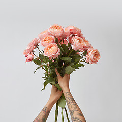 Image showing the girl is holding a bouquet of fresh pink roses,