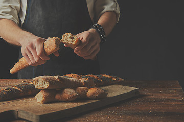 Image showing The baker keeps the baguette halves in his hands.