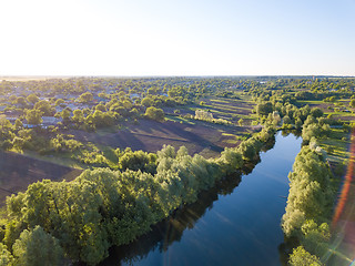 Image showing aerial view of a blue lake, green forest and blue sky