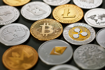 Image showing Set of different gold and silver coins of crypto-currencies on a dark background with bright light. Top view