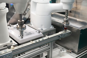 Image showing Automatic robot arm working in industrial environment sorting out screws