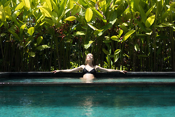 Image showing Sensual young woman relaxing in outdoor spa infinity swimming pool surrounded with lush tropical greenery of Ubud, Bali.