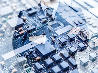 Image showing Businessman standing with folded arms in a classic navy blue suit against pc motherboard chip photo layer.