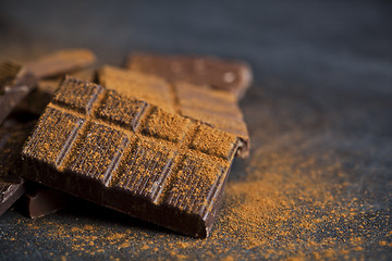 Image showing Chocolate stacked on black background. Chocolate bar pieces heap