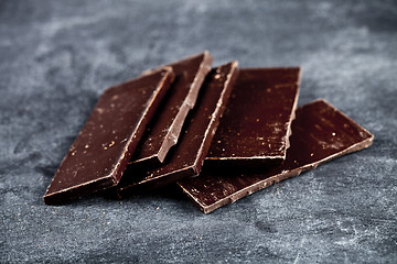 Image showing Chunks of broken dark chocolate stacked on grey background.