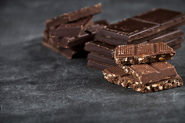 Image showing Chunks of broken chocolate stacked on black board. 