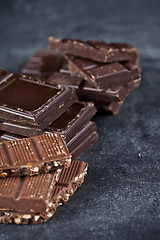 Image showing Chunks of broken chocolate stacked on black board. 