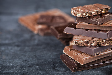 Image showing Chunks of broken chocolate stacked on black board.