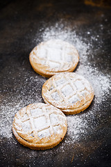 Image showing Fresh baked tarts with chocolate filling and sugar powder on bla