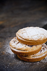 Image showing Fresh baked tarts with chocolate filling and sugar powder on bla