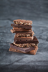 Image showing Chocolate bar pieces stack on black background. Sweet food photo