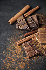 Image showing Chocolate bar pieces heap witn cinnamon powder and sticks. Broke