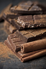 Image showing Chocolate bar pieces heap witn cinnamon powder and sticks. Broke