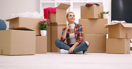 Image showing woman with many cardboard boxes sitting on floor