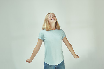 Image showing The happy freckled woman standing and smiling against gray background.