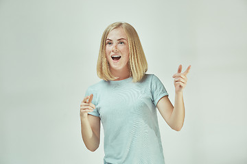 Image showing The happy freckled woman standing and smiling against gray background.