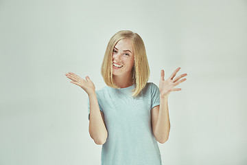 Image showing The happy freckled woman standing and smiling against gray background.